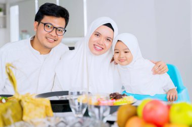 Mübarek bayramında evde yemek yerken kızlarını kucaklayan mutlu ebeveynler.