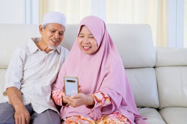 Müslüman yaşlı çift oturma odasında otururken aileleriyle video görüşmesi yapıyor.