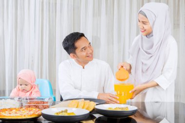 Bayram bayramında evde birlikte yemek yerken taze içki koyan genç bir kadın.