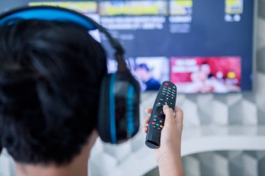 Evde televizyon izlerken çocuğun kulaklık ve uzaktan kumanda kullanmasının arka planı.