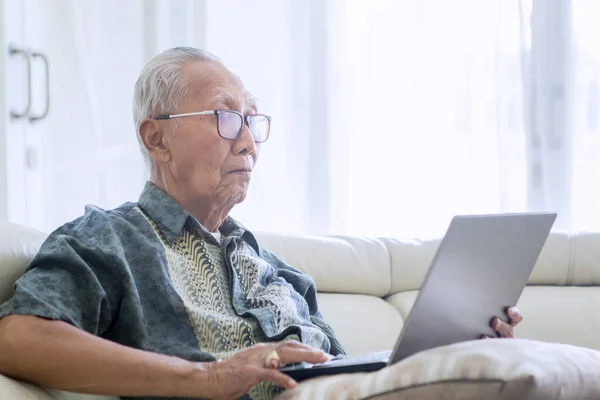Старик Наслаждается Отдыхом Пользуясь Ноутбуком Диване Застрелен Дома — стоковое фото