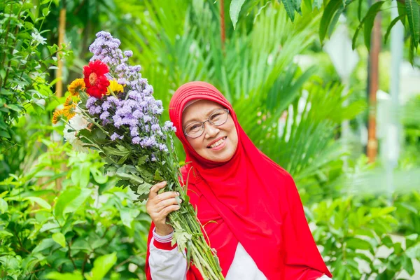 Vieja Musulmana Sonriendo Cámara Mientras Sostiene Flores Jardín —  Fotos de Stock