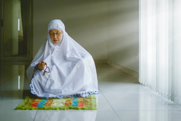 老太婆坐在清真寺明亮的窗前 在做完沙拉后 举着祈祷珠子要吃石榴 — 图库照片