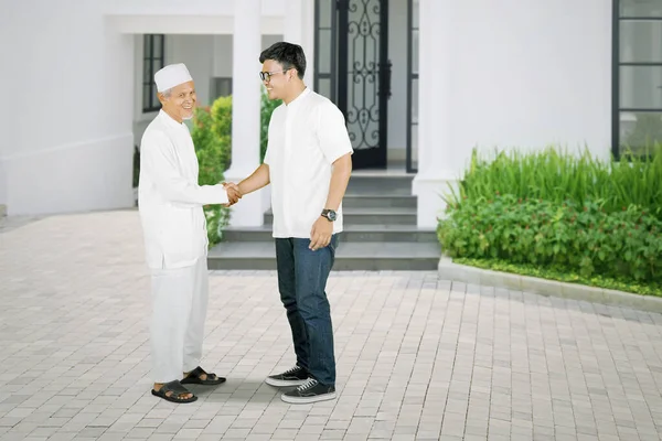 家の前に立ちながら イード ムバラクのお祝いで息子と握手をする老人 — ストック写真