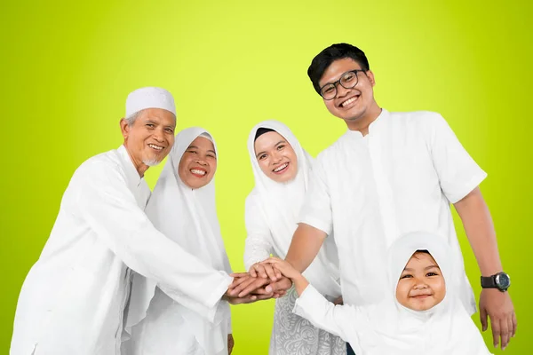 三代穆斯林家庭手拉手站在有绿色背景的工作室里庆祝开斋节的低视角图像 — 图库照片
