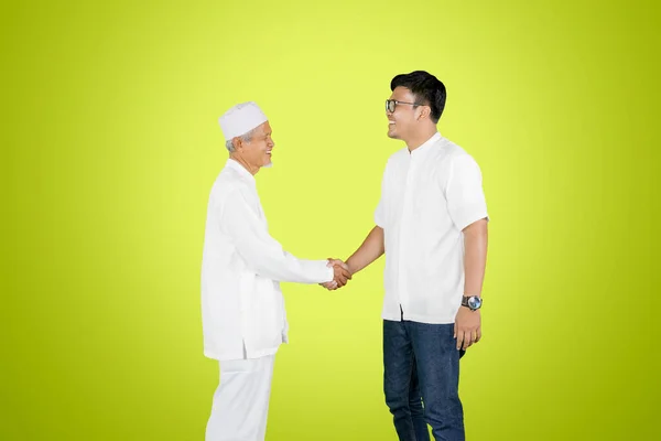 緑の画面の背景を持つスタジオに立っている間 若い男は彼の父と一緒にEid Mubarakのお祝いで握手 — ストック写真
