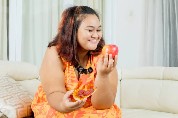 Obesitas Vrouw Die Een Rode Appel Kiest Terwijl Pizza Woonkamer — Stockfoto