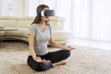 Spor kadın oturma odasında VR gözlüğü takarken yoga egzersizi yapıyor. Evde vuruldu.