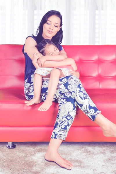 Young Woman Hugging Her Daughter While Sitting Couch Shot Home — Stockfoto