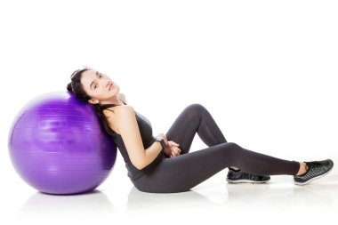Beautiful woman leaning on the yoga ball while resting after workout in the studio. Isolated on white background