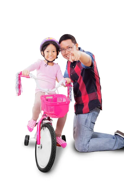 아빠는 딸에게 스튜디오에서 자전거타는 가르치면서 무언가를가리키고 있습니다 배경에 고립됨 — 스톡 사진