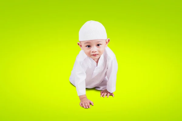 男婴身穿穆斯林服装 爬进有绿色背景的工作室 — 图库照片