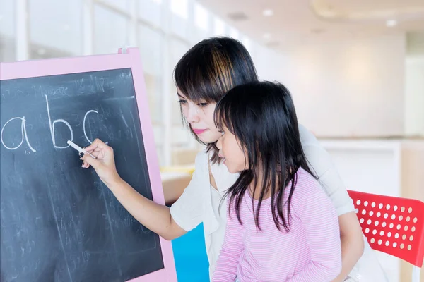 Vrouwelijke Lerares Die Alfabet Schrijft Het Schoolbord Terwijl Haar Leerling — Stockfoto