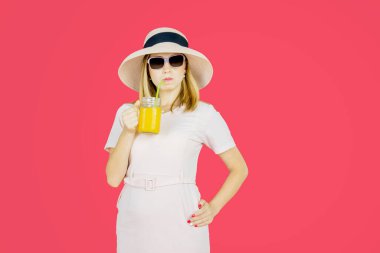 Gururlu genç kadın bir bardak portakal suyu içerken stüdyoda duruyor.