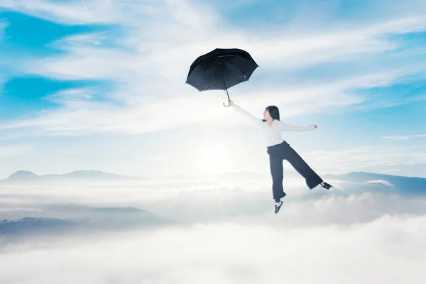 年轻的女商人拿着雨伞在蓝天中飞翔 — 图库照片