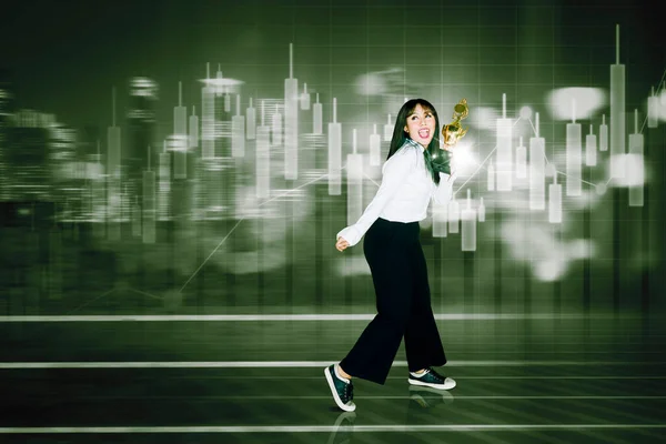 Happy Businesswoman Holding Trophy While Standing Candlestick Chart Background — ストック写真