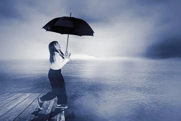 若い実業家が傘を持ちながら霧の朝木の桟橋を歩いている — ストック写真