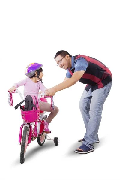 年轻父亲在工作室教女儿骑自行车的肖像 因白人背景而被隔离 — 图库照片