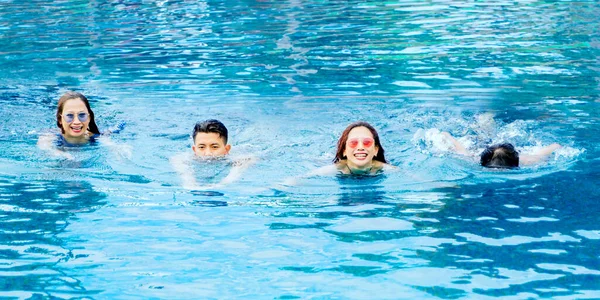 一群快乐的年轻人一边在游泳池边游泳一边享受暑假 — 图库照片
