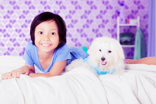 カメラを向けると 幸せな女の子はベッドの上でマルチ犬と寝そべっていた 家で撃たれた — ストック写真