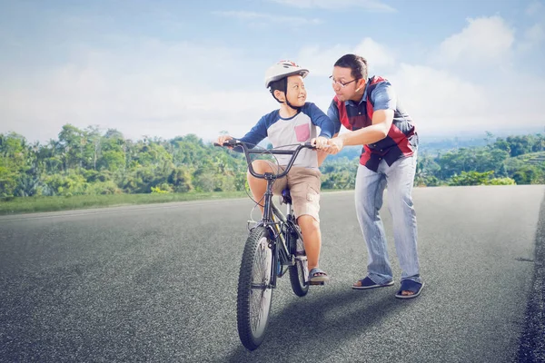 Menino Ajudado Por Seu Pai Enquanto Aprendia Andar Bicicleta Estrada — Fotografia de Stock