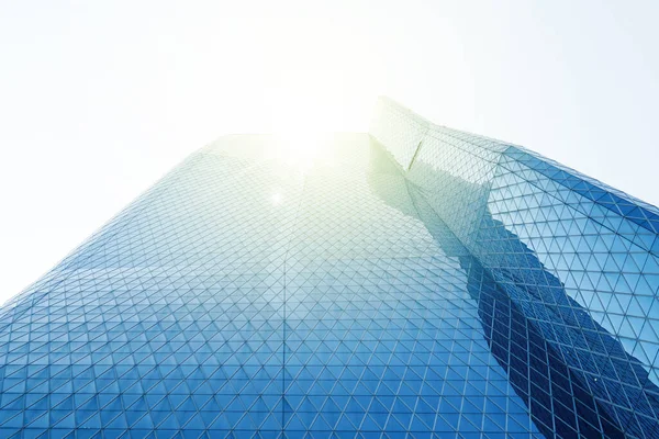 Mavi gökyüzü arkaplanının altındaki ofis binasının düşük açılı görünümü ve güneş ışığı arka planı