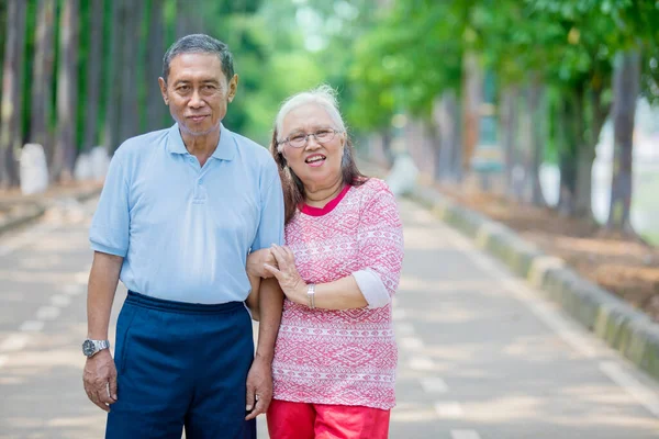 Senior Woman Embracing Her Husband Smiling Camera While Standing Road — Stock Photo, Image