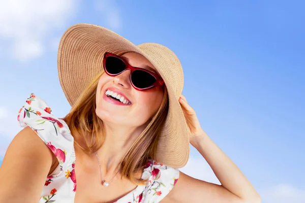 ビーチで青空を背景に写真を撮りながら帽子とサングラスをかけながら笑顔の女性のクローズアップ — ストック写真