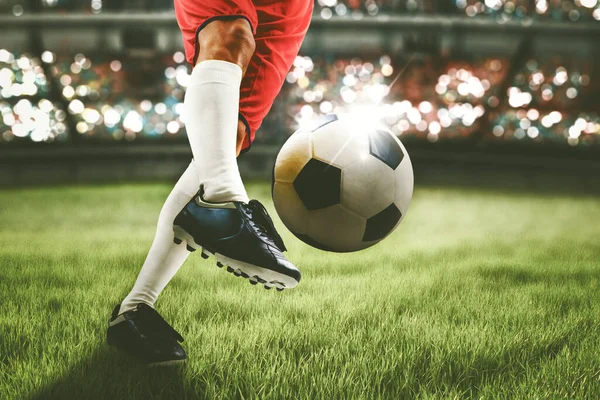 Close up of soccer player feet shooting a ball with powerful toward a goal while playing on a stadium with crowds spectators background