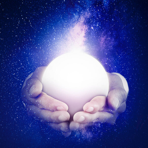 Close up of unknown hands holding a bright moon in the night sky with milky way background