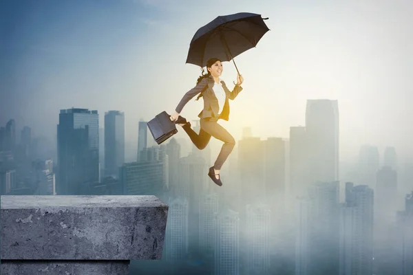 Kadını Elinde Şemsiyeyle Çatıdan Atlarken Bir Bavul Taşıyor — Stok fotoğraf