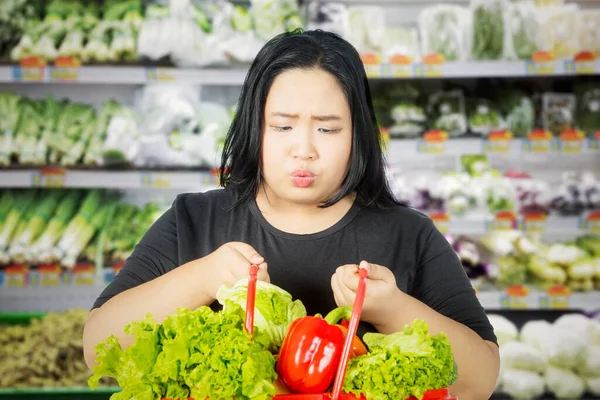 Doubtful Fat Woman Holding Full Box Vegetables While Standing Supermarket — Foto Stock