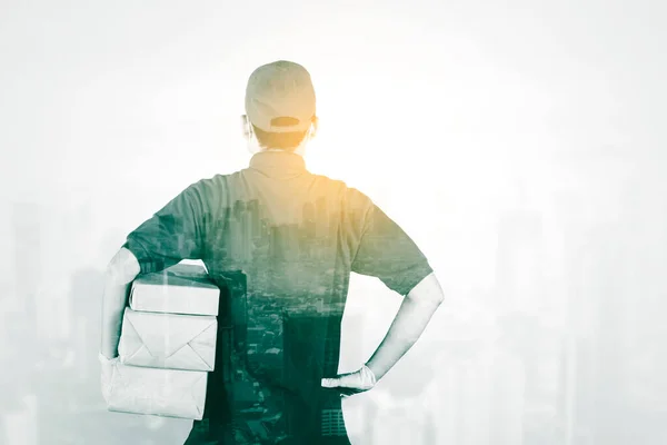 Double Exposure Male Courier Holding Package While Standing Cityscape Background — ストック写真