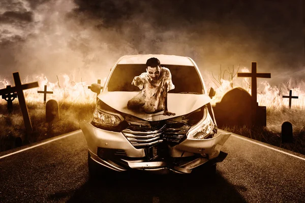 気味の悪い男の幽霊座っています壊れた車のフードとともに燃焼墓の背景夜の時間 — ストック写真