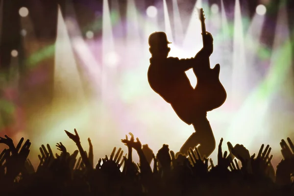 ファンの近くのコンサートステージに立ちながらエレキギターを弾く男性ギタリストのシルエット — ストック写真