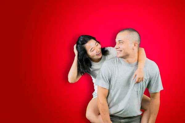 Jovem Feliz Piggybacking Sua Esposa Enquanto Estúdio Com Fundo Vermelho — Fotografia de Stock