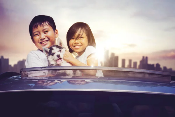 Δύο Χαμογελαστά Παιδιά Αγκαλιάζουν Σκύλο Τους Στην Ηλιοροφή Του Αυτοκινήτου — Φωτογραφία Αρχείου