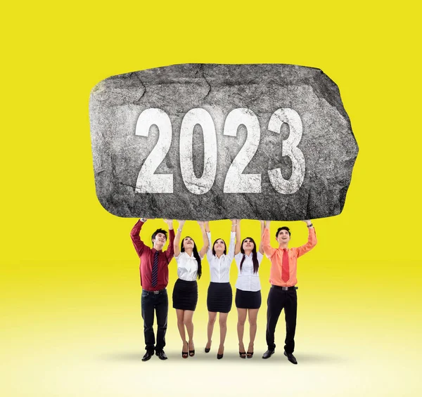 Grupo Jóvenes Empresarios Levantando Una Gran Piedra Con 2023 Números — Foto de Stock