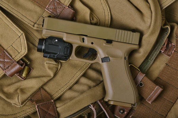 Weapons and military gun equipment for army with tactical flashlight, Semi-automatic handgun, 9mm sand color polymer pistol.