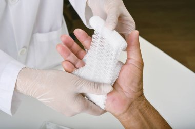 Doktor yaralarını sarar, hastanın elini bandajlar, el tedavisi, hastanede hastanın parmağını tedavi eder..