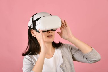 Asian woman using vr glasses, Watching movie and playing video games from virtual reality headset, Young woman amazing with new experience by vr technology, Studio shot.