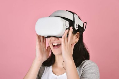 Videolar kullanan Asyalı bir kadın, sanal gerçeklik kulaklığından video oyunu oynayan, video teknolojisi ile yeni deneyimi olan genç bir kadın, Stüdyo çekimi..