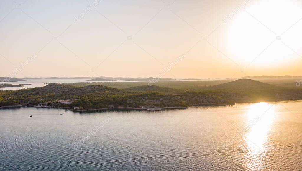 Aerial drone view of sunset over Kornati islands near the Sibenik city, Croatia. Water bay with boats ans soft sun light.