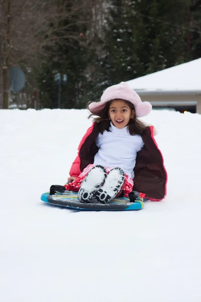 Est indiano ragazza toboganning in il neve — Foto Stock