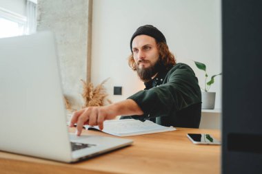 Öğrenci hipster üniversitede okurken ev ödevi yapıyor. Sakallı adam çevrimiçi ders dinlerken not alıyor.