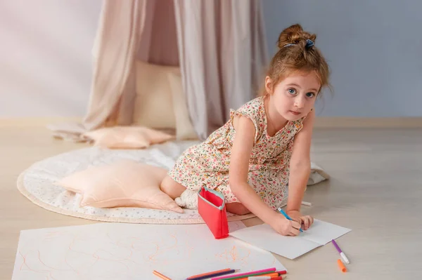 Маленькая девочка рисует комнату на полу. Солнечные лучи освещают комнату из окна.. — стоковое фото