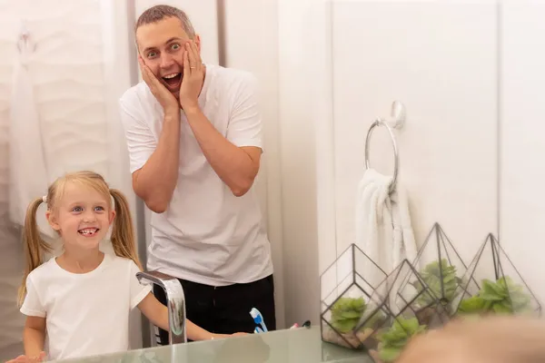 Dochter toont vader gevallen melk tand weerspiegeld in spiegel in heldere badkamer — Stockfoto