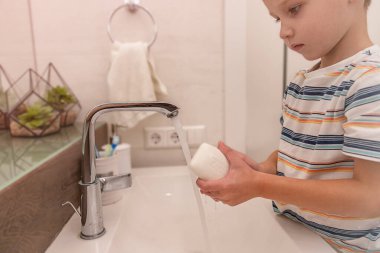 Beyaz çocuk ellerini banyo suyuyla ve sabunla yıkar.