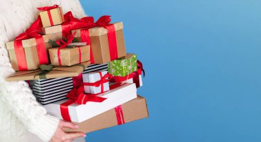 Mavi uzun arka plandaki adam elinde bir sürü farklı hediye tutuyor.