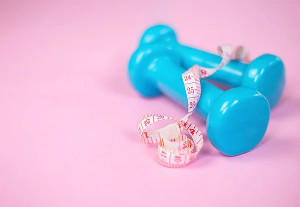 Two blue dumbbells with measuring tape on pink background, side view, copy space — 图库照片